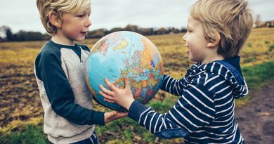 Two little boys with a globe outdoors